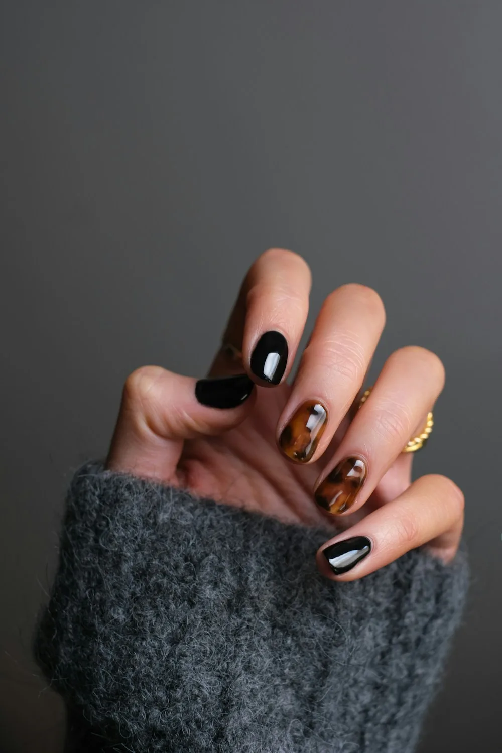 A hand with a dark manicured nail finish