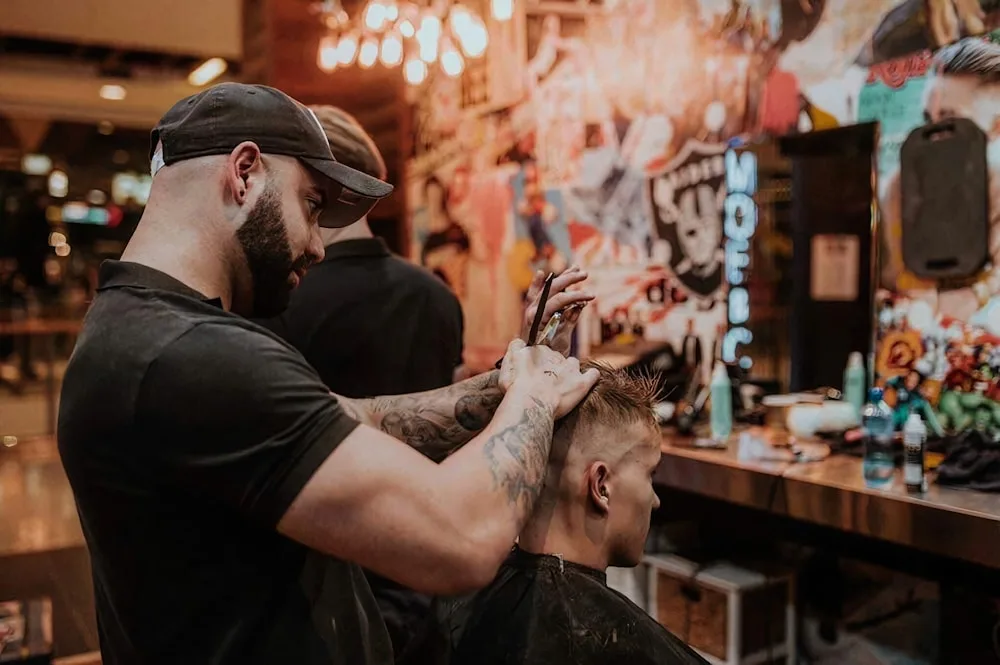 A barber shaping a client's fade with scissors
