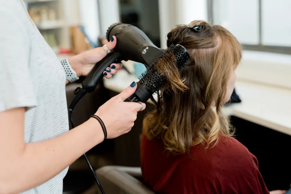 Stylist blow-drying and shaping a woman's hair